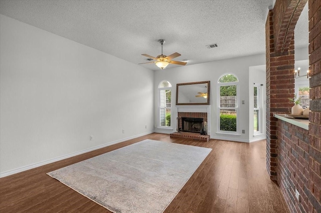 unfurnished living room with wood finished floors, baseboards, a textured ceiling, a ceiling fan, and a fireplace