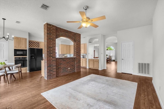living room featuring dark wood-style floors, arched walkways, ceiling fan, a chandelier, and brick wall