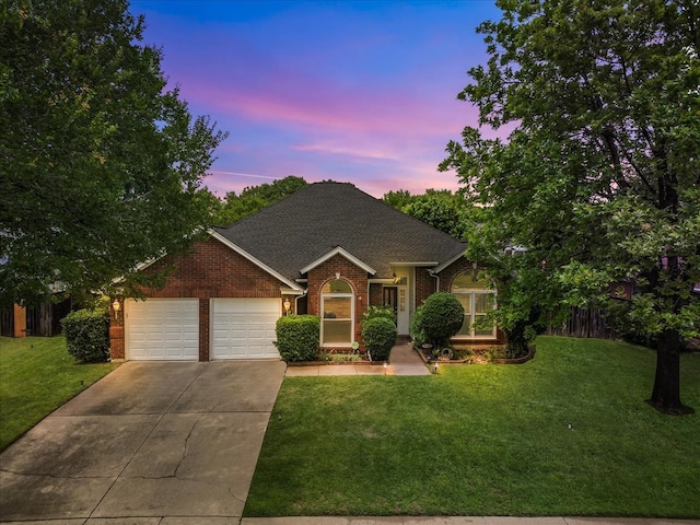 view of front facade featuring brick siding, concrete driveway, an attached garage, a lawn, and a shingled roof