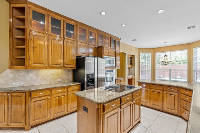 2609 Green Oak Dr, Carrollton, TX 75010 - kitchen featuring stainless steel appliances, brown cabinetry, a chandelier, backsplash, and a kitchen island