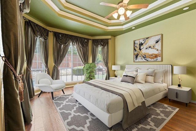 2609 Green Oak Dr, Carrollton, TX 75010 - bedroom featuring ornamental molding, a tray ceiling, wood finished floors, and a ceiling fan