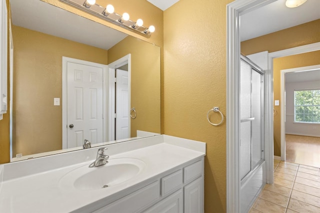 2609 Green Oak Dr, Carrollton, TX 75010 - bathroom featuring vanity, tile patterned floors, a textured wall, and combined bath / shower with glass door