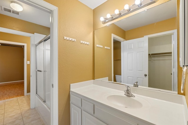 2609 Green Oak Dr, Carrollton, TX 75010 - bathroom featuring vanity, a textured wall, toilet, tile patterned flooring, and enclosed tub / shower combo