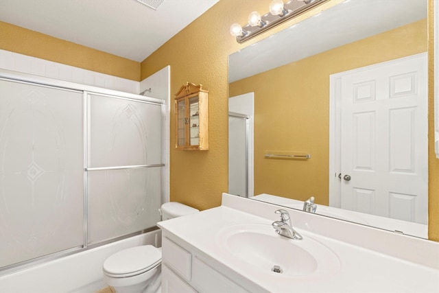 2609 Green Oak Dr, Carrollton, TX 75010 - bathroom featuring a textured wall, vanity, toilet, and bath / shower combo with glass door