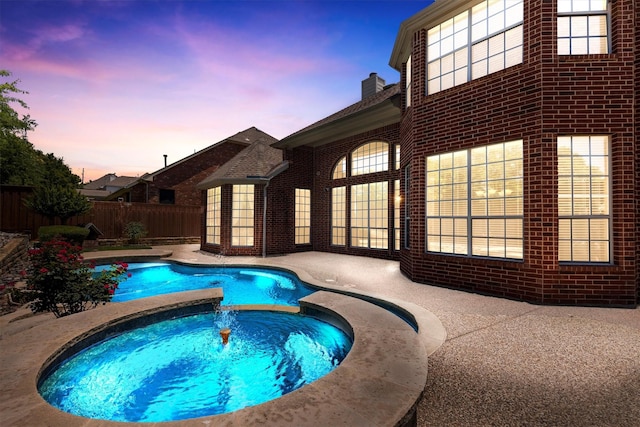 2609 Green Oak Dr, Carrollton, TX 75010 - pool at dusk featuring a pool with connected hot tub and a patio