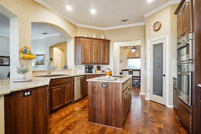 7300 Bishop Ct, Fort Worth, TX 76179 - kitchen featuring appliances with stainless steel finishes, a sink, a kitchen island, dark wood-style flooring, and ornamental molding