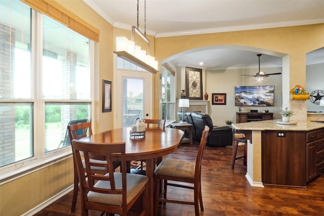 7300 Bishop Ct, Fort Worth, TX 76179 - dining space with a tiled fireplace, arched walkways, plenty of natural light, dark wood-style flooring, and crown molding