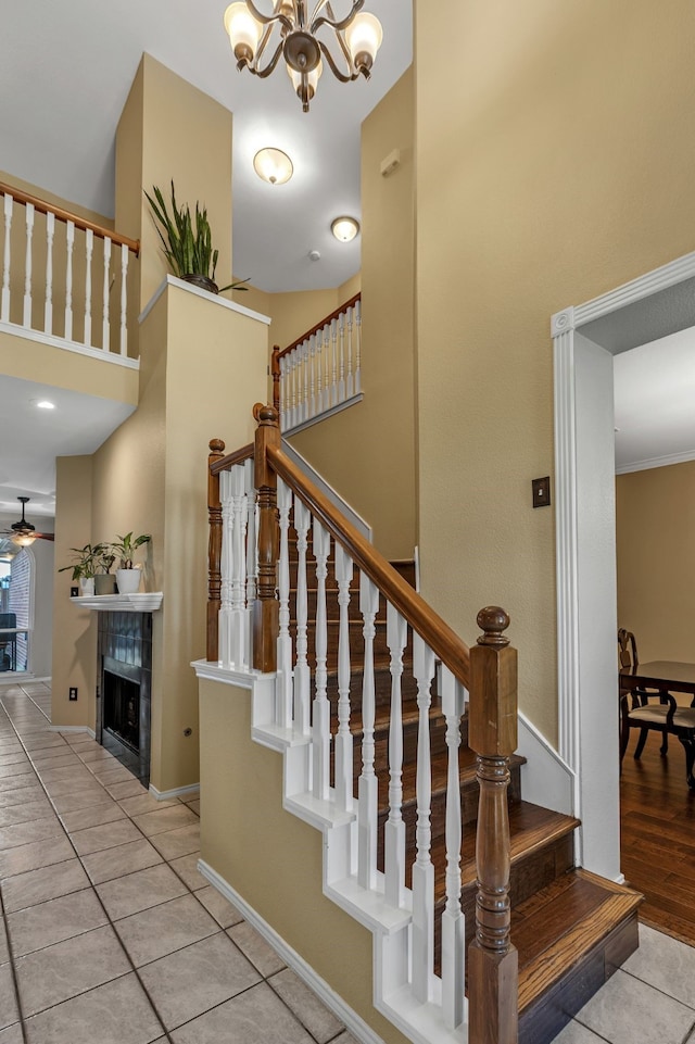 533 Cameron Ln, Allen, TX 75002 - staircase with a high ceiling, tile patterned floors, a chandelier, a tiled fireplace, and baseboards