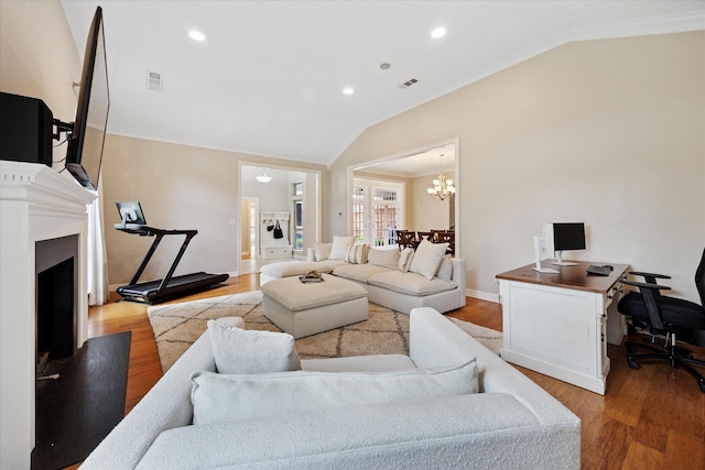 living room with lofted ceiling, ornamental molding, a chandelier, light wood-style flooring, and a fireplace