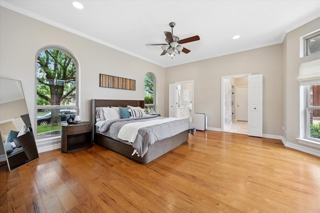 bedroom with light wood-type flooring, crown molding, baseboards, ensuite bath, and recessed lighting