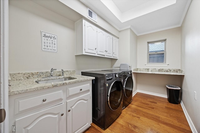 laundry area with washing machine and clothes dryer, light wood-style floors, cabinet space, crown molding, and baseboards