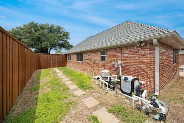 rear view of property featuring brick siding, a shingled roof, and a fenced backyard