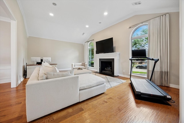 living room featuring lofted ceiling, light wood-style floors, a fireplace, recessed lighting, and crown molding