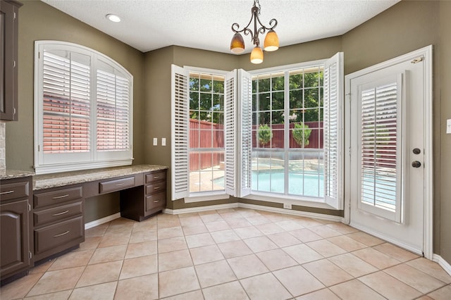 6748 Bastille Dr, Plano, TX 75024 - unfurnished dining area featuring a chandelier, a textured ceiling, baseboards, and light tile patterned flooring