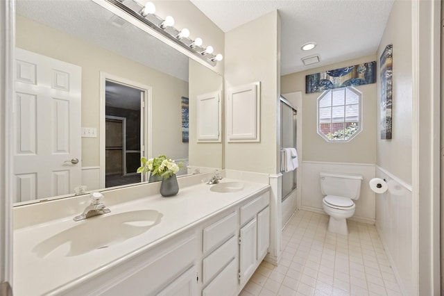 6748 Bastille Dr, Plano, TX 75024 - bathroom with toilet, tile patterned flooring, bath / shower combo with glass door, double vanity, and a textured ceiling