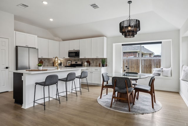 12306 Ark Rd, Frisco, TX 75035 - kitchen featuring stainless steel appliances, vaulted ceiling, a chandelier, decorative backsplash, and white cabinets