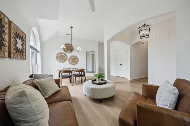 12306 Ark Rd, Frisco, TX 75035 - living room featuring a chandelier, arched walkways, light wood finished floors, and vaulted ceiling