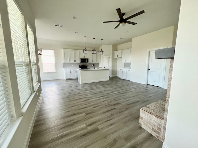 unfurnished living room featuring a ceiling fan, wood finished floors, baseboards, and a sink