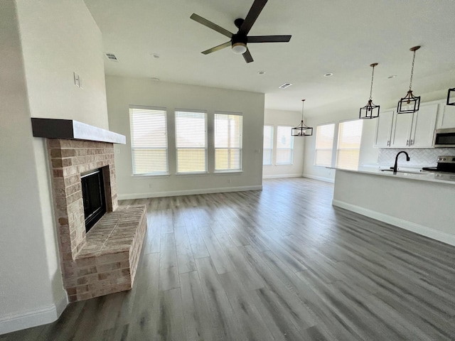 unfurnished living room featuring baseboards, a ceiling fan, and wood finished floors