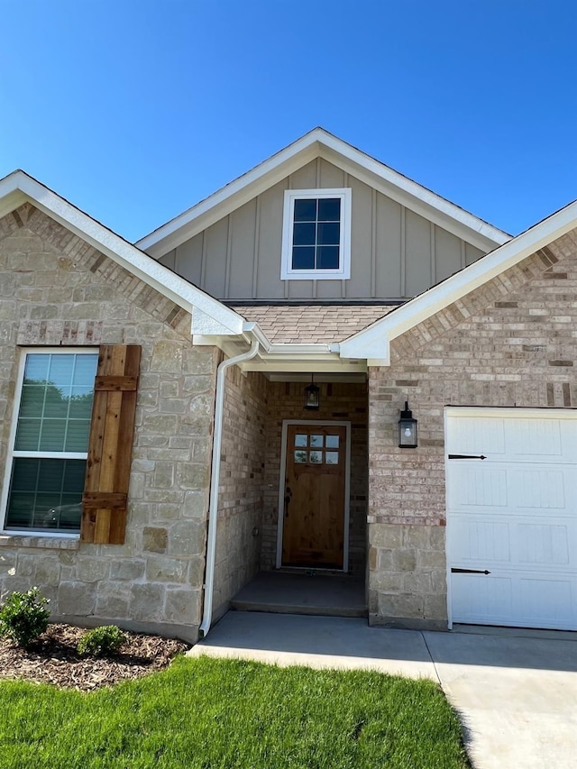 view of exterior entry featuring board and batten siding, stone siding, and an attached garage