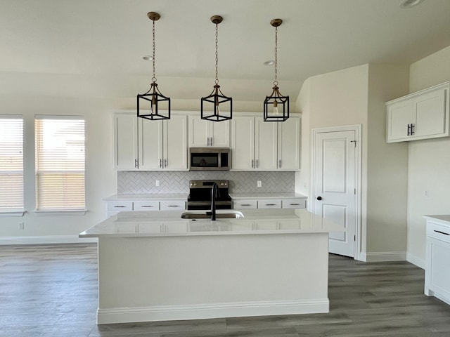 kitchen with stainless steel appliances, backsplash, a sink, and wood finished floors