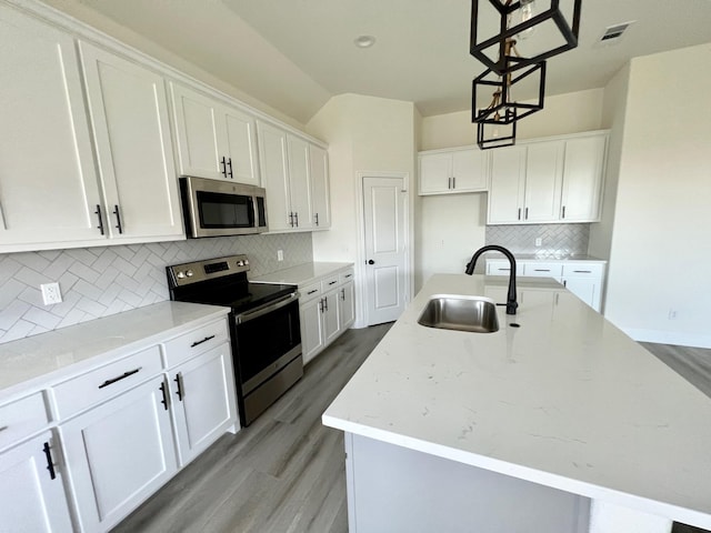 kitchen with stainless steel appliances, a sink, light wood-type flooring, and a center island with sink