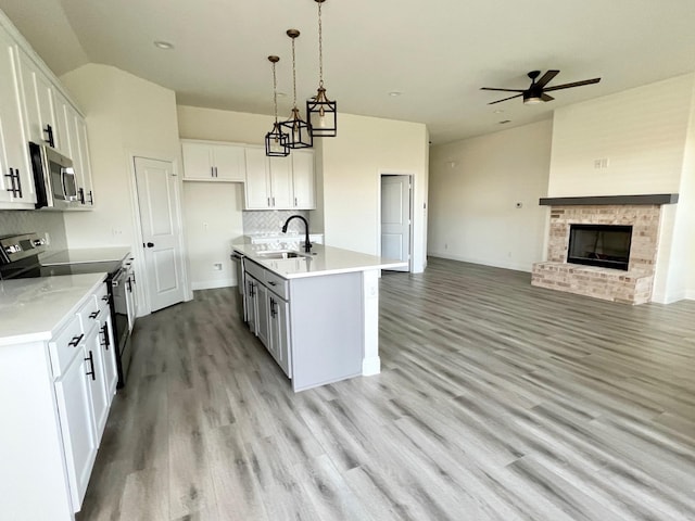 kitchen featuring appliances with stainless steel finishes, a sink, open floor plan, vaulted ceiling, and a fireplace