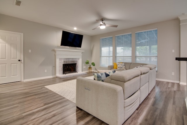 living area with a ceiling fan, a fireplace, wood finished floors, baseboards, and recessed lighting