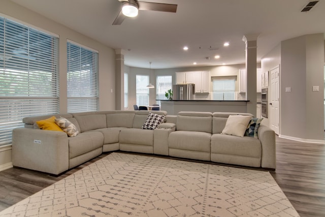 living area featuring ornate columns, wood finished floors, ceiling fan, baseboards, and recessed lighting