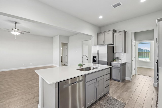 kitchen with gray cabinets, appliances with stainless steel finishes, a sink, light wood-type flooring, and recessed lighting