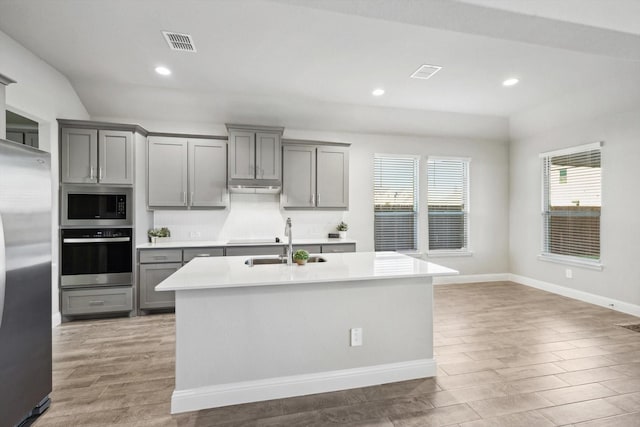 kitchen featuring stainless steel appliances, gray cabinets, a sink, light wood-style flooring, and recessed lighting