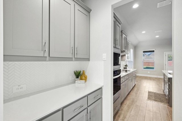 kitchen with gray cabinetry, stainless steel appliances, backsplash, recessed lighting, and light countertops