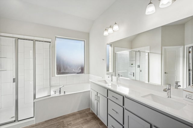 full bath with a shower stall, wood finished floors, lofted ceiling, a garden tub, and double vanity