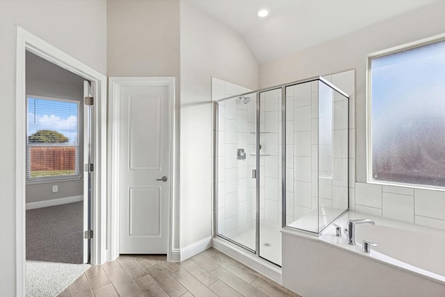 bathroom featuring a stall shower, lofted ceiling, a bath, baseboards, and recessed lighting