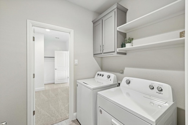 clothes washing area with washing machine and dryer, cabinet space, baseboards, and light colored carpet