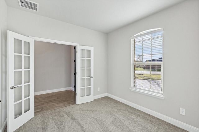 empty room featuring french doors, carpet floors, and baseboards