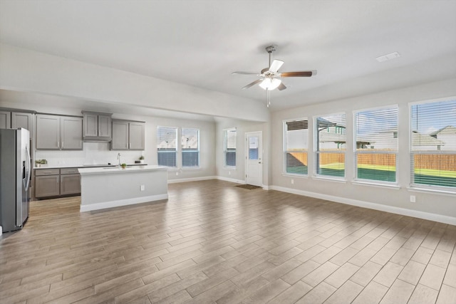 kitchen featuring stainless steel fridge with ice dispenser, gray cabinets, open floor plan, ceiling fan, and light wood finished floors