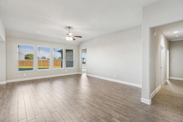 spare room featuring a ceiling fan, wood finished floors, and baseboards