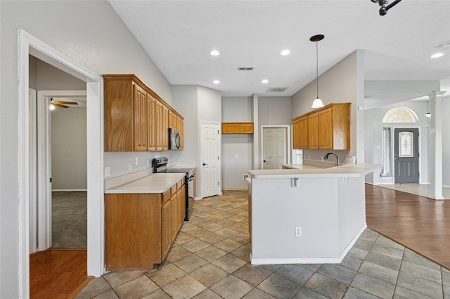 kitchen featuring range with electric stovetop, stainless steel microwave, a peninsula, baseboards, and light countertops