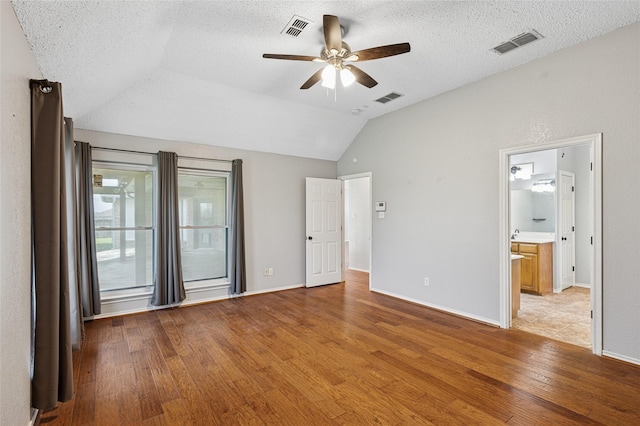 unfurnished bedroom featuring light wood-style flooring, lofted ceiling, baseboards, a textured ceiling, and a ceiling fan