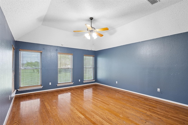 unfurnished room with wood finished floors, a textured wall, a ceiling fan, lofted ceiling, and baseboards