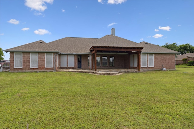 back of property with roof with shingles, brick siding, and a patio area