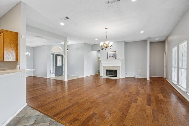 unfurnished living room with a chandelier, recessed lighting, a high end fireplace, wood finished floors, and baseboards