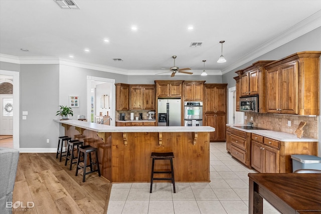 309 Slate Cir, Haughton, LA 71037 - kitchen featuring appliances with stainless steel finishes, brown cabinetry, a peninsula, a kitchen bar, and recessed lighting