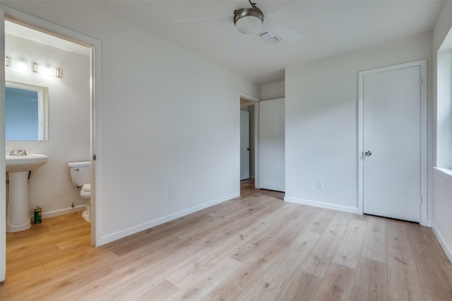unfurnished bedroom with wood finished floors, ensuite bath, and baseboards