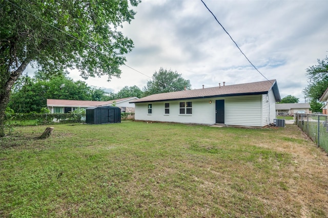 rear view of property with a storage shed, central AC, and an outbuilding