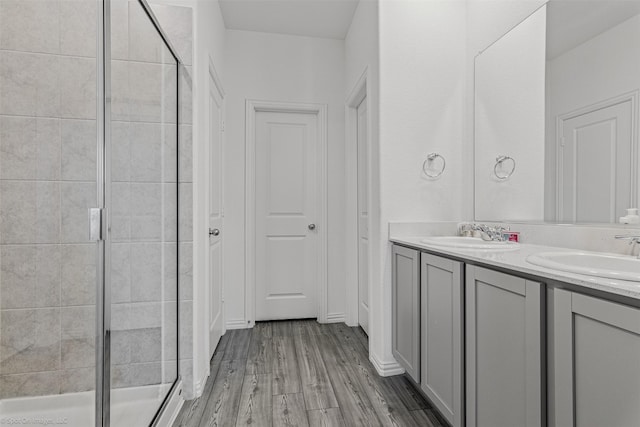 full bathroom featuring a stall shower, double vanity, and wood finished floors