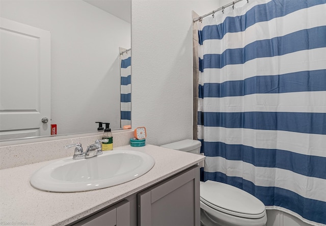 bathroom featuring toilet, vanity, curtained shower, and a textured wall