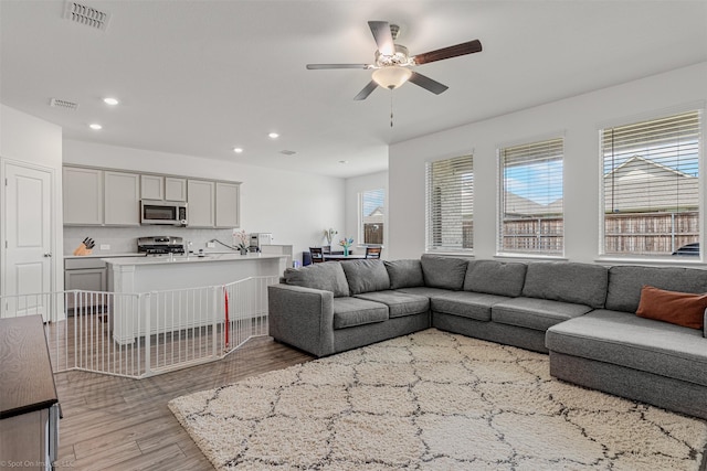 living room featuring a ceiling fan, recessed lighting, and light wood-type flooring
