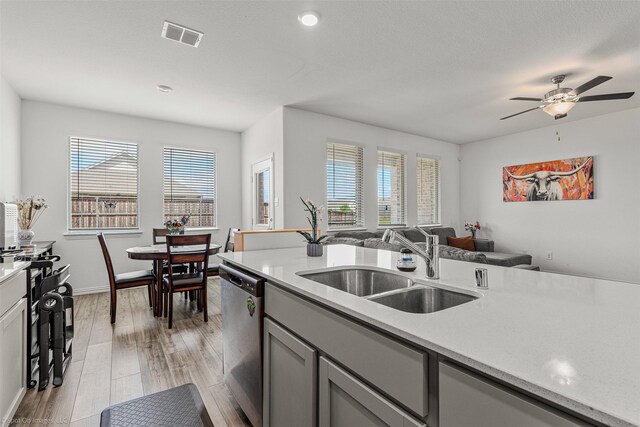 kitchen featuring dishwasher, gray cabinets, a sink, light countertops, and recessed lighting